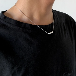 Detail of silver snake chain necklace with curved bar pendant on male model