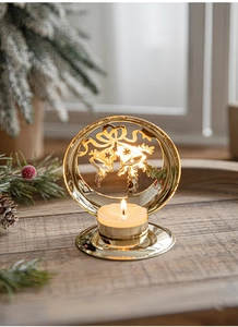Close-up of golden Christmas bell candle holder with a tea light on a wooden table