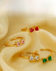 Détail de quatre bagues nœud colorées en or 18 carats avec zircon sur soie jaune