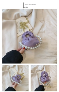 Close-up of purple pleated mini bag featuring large pearl handle and gold chain strap