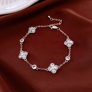 Close-up of silver flower bracelet with zircons on dark red velvet background