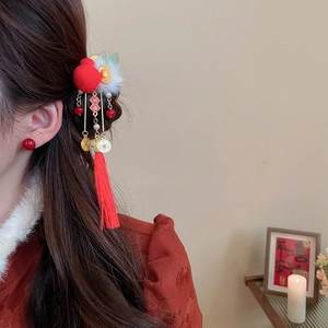 Detail of red knitted pompom hair clip with tassels and Fu character for New Year