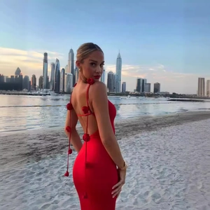 Detail of red backless dress featuring 3D floral accents and sleek straps by the coast