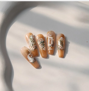 Detailed close-up of 3D embossed swan and rose nail art with pearls on amber glitter finish