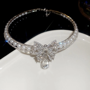 Close-up of luxury pearl necklace with sparkling rhinestone bow and teardrop crystal pendant