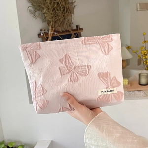 Detail showing high-capacity pink jacquard makeup bag with embossed bow patterns and fabric texture