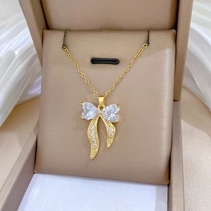 Detailed view of a gold bow necklace featuring heart-shaped stones and crystal embellishments