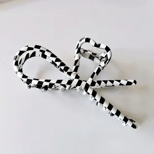 Detail of checkered bow hair claw clip with heart silhouette and metal spring