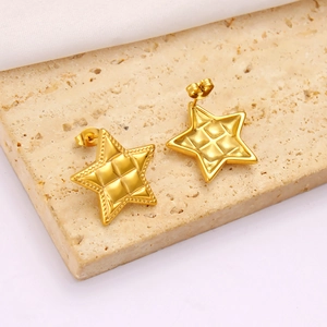 Macro detail of gold star earrings with quilted texture and beaded edges on marble