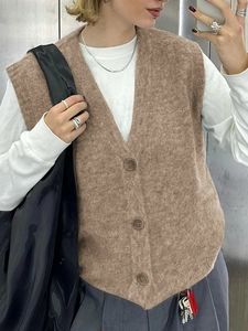 Dettaglio del gilet in maglia color cammello con scollo a V e bottoni frontali