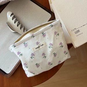 Blumen Kosmetiktasche mit lila Muster und Stofflabel auf einem Holztablett