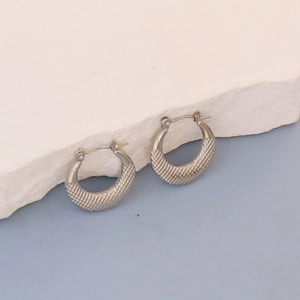 Detail view of silver oval hoop earrings with grid embossed texture on stone