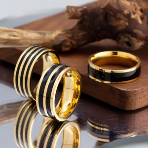 Three-piece gold stainless steel ring set with black enamel stripes on wooden background