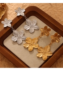 Détail de boucles d'oreilles fleur or et argent avec texture métal brossé et perles