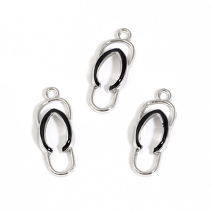 Detailed macro view of three silver alloy flip-flop charms with black enamel details