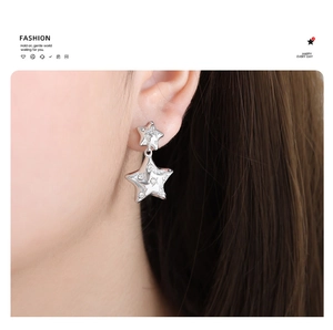 Macro shot of silver star-shaped earrings with glittering cubic zirconia on a model