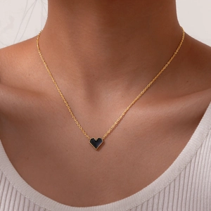Elegant gold chain necklace with black heart pendant worn by a model in minimalist style