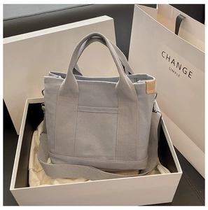 Close-up of a minimalist grey canvas tote bag elegantly placed inside a white gift box