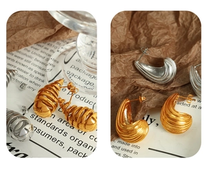 Detailed view of conch spiral earrings in gold and silver finish on vintage background