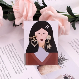 Detailed view of gold asymmetrical heart earrings with rhinestones on a display card