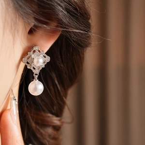 Detailed close-up of vintage silver earrings with clear zircons and elegant pearls on model