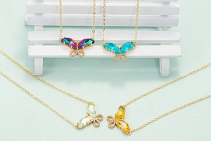 Macro view of butterfly pendant with colorful gemstones and golden link chain detail