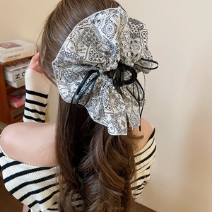 Rear view of a model wearing the large paisley bow hair claw with pearl details