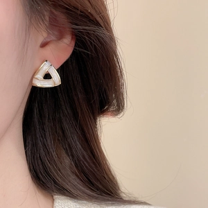 Detailed view of minimalist triangular gold-rimmed earrings with white enamel finish
