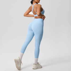 Detail of light blue cross-back sports bra and high-waist yoga leggings on model