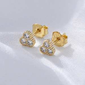Macro shot of 925 silver gold-plated stud earrings with three sparkling round zircons