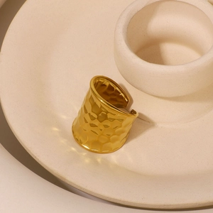 Golden chunky open ring with water ripple hammered texture on ceramic tray