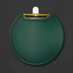 Emerald green round standing cutting board with a gold handle on a dark textured background