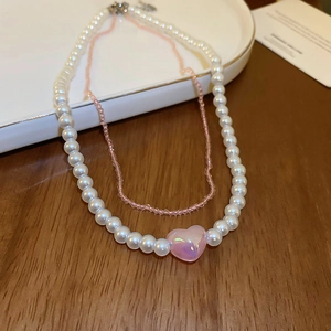 Detail of double-layer necklace with faux pearls, pink beads, and a heart pendant