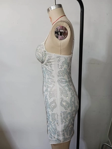 Detailed view of white mini dress featuring intricate silver rhinestones and mesh patchwork