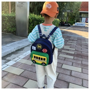 Outdoor view of children's blue mini backpack with yellow school bus design and traffic decals