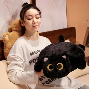 Coussin peluche chat noir doux tenu par une personne dans une chambre à coucher chaude