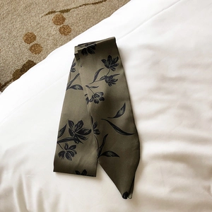 Detail of olive green floral satin scarf ribbon with elegant vintage patterns on white fabric