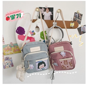 Détail de deux sacs bandoulière en toile avec poches transparentes et breloques d'ours