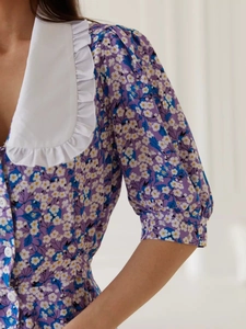 Detail of floral purple dress showing white Peter Pan collar and buttoned front