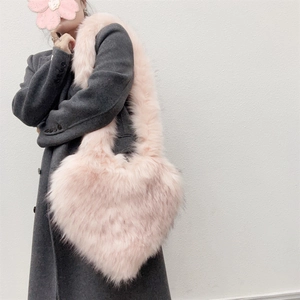 Close-up of pink faux fur heart-shaped bag texture against grey woolen coat
