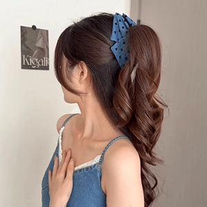Detail einer blauen Denim-Haarklammer mit schwarzen Punkten in braunem Haar