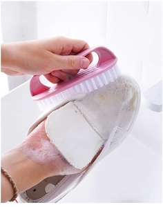 Pink scrubbing brush cleaning white canvas shoes with thick foam on tiled background