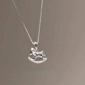 Gros plan détaillé d'un collier pendentif cheval à bascule argenté serti de zircons