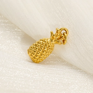 Detailed view of a golden stainless steel pineapple pendant on soft white fabric