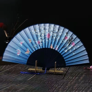 Traditional blue folding fan featuring pink floral and butterfly patterns on a wooden stand