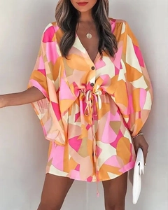 Detail of V-neck summer dress featuring colorful geometric print and drawstring waist tie