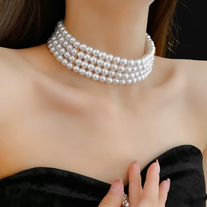 Gros plan d'un collier ras du cou à quatre rangs de perles avec fermoirs dorés