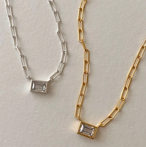 Detail of gold and silver necklaces with rectangular cubic zirconia and paperclip chains