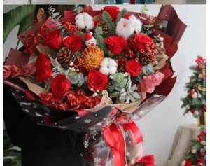 Christmas bouquet featuring red roses, pine cones, and Santa Claus doll in gift wrap