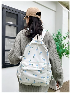 Detail view of white nylon backpack with blue tulip floral print on a model's back